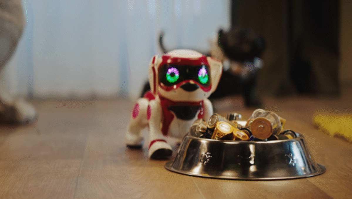Ein kleiner Spielzeugroboterhund bewegt seinen Kopf seitlich hin und her, weil er in seinem Fressnapf einen kleinen Berg alter Batterien hat.